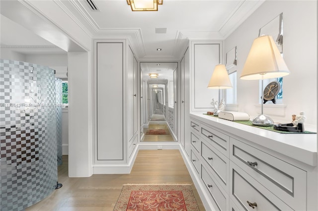 hallway with light wood-type flooring and crown molding