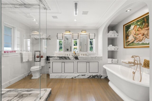 bathroom featuring ornamental molding, toilet, wood-type flooring, a tub, and vanity