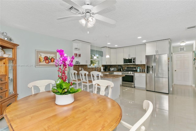 dining space featuring visible vents, ceiling fan, and a textured ceiling