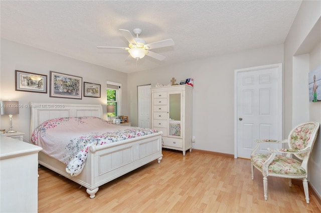 bedroom with ceiling fan, a textured ceiling, and light wood-type flooring