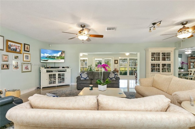 living area featuring baseboards, visible vents, and a ceiling fan