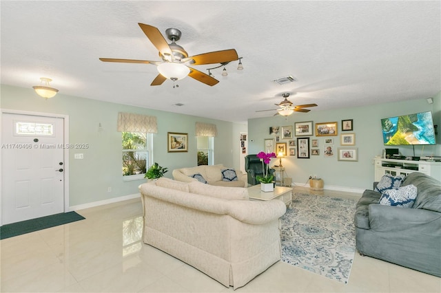 living room featuring a textured ceiling, visible vents, and baseboards