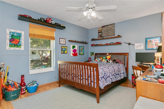 bedroom with baseboards, a textured ceiling, a ceiling fan, and wood finished floors