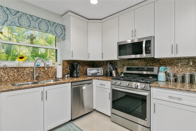 kitchen featuring stainless steel appliances, a sink, white cabinets, and decorative backsplash