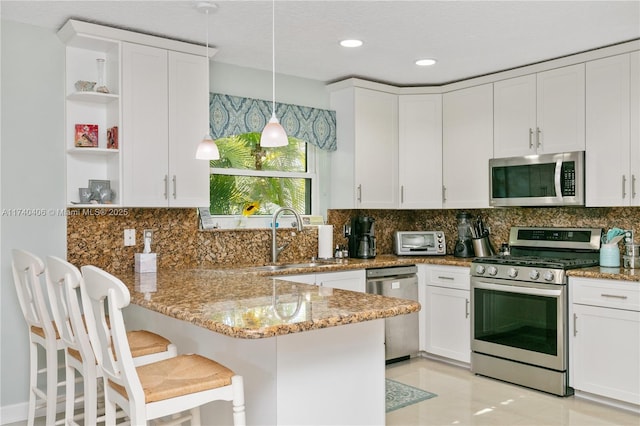 kitchen with sink, a kitchen breakfast bar, hanging light fixtures, kitchen peninsula, and stainless steel appliances