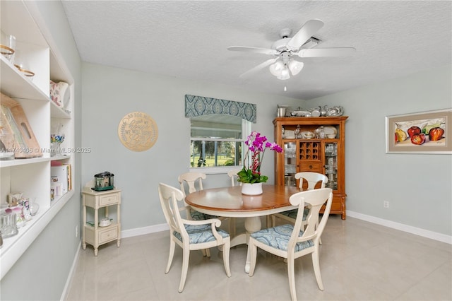 dining area featuring ceiling fan, light tile patterned floors, and a textured ceiling