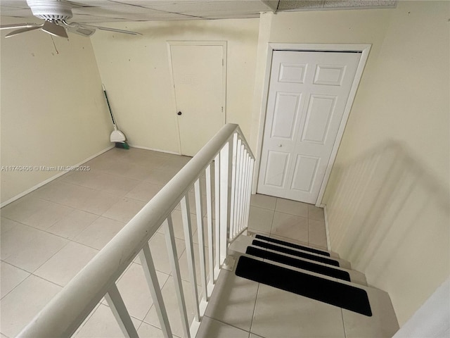 stairway featuring tile patterned flooring, a ceiling fan, and baseboards