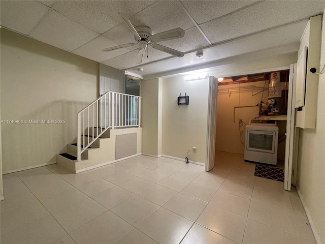 spare room featuring light tile patterned floors, a paneled ceiling, washer / clothes dryer, stairway, and baseboards