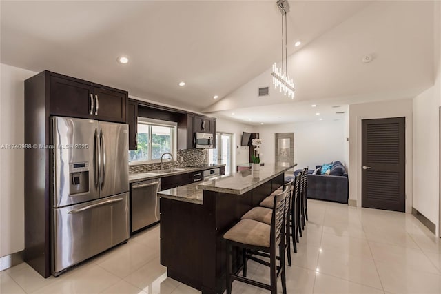 kitchen with a breakfast bar, a center island, appliances with stainless steel finishes, stone counters, and backsplash