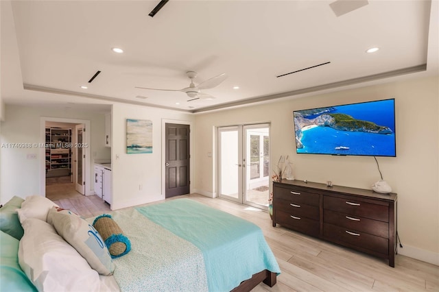 bedroom with light hardwood / wood-style flooring, access to outside, a raised ceiling, and french doors