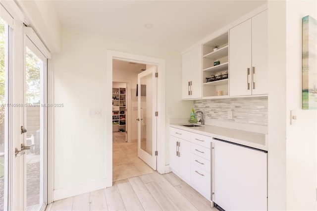 kitchen featuring tasteful backsplash, sink, white cabinets, light hardwood / wood-style floors, and french doors