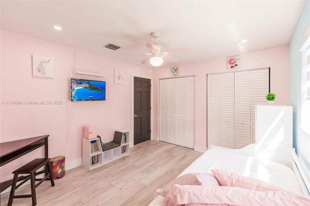 bedroom featuring two closets, ceiling fan, and light wood-type flooring