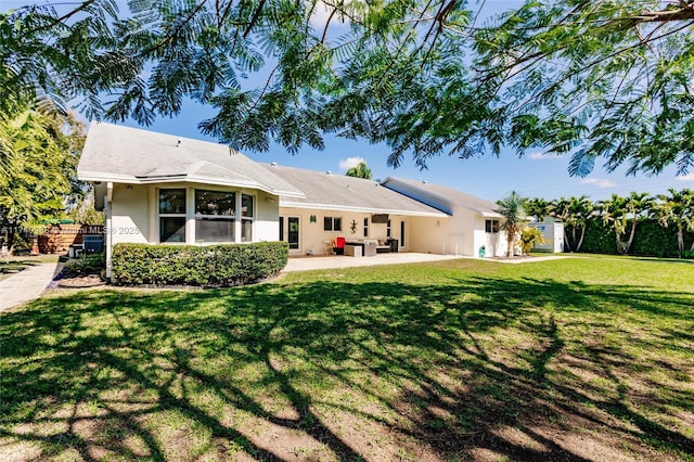 rear view of property featuring a patio and a lawn