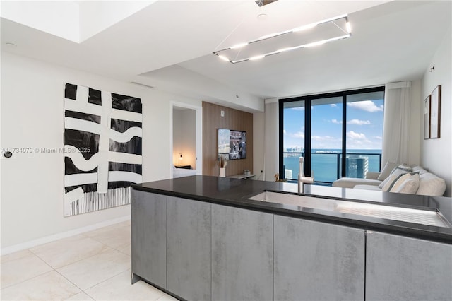 kitchen with light tile patterned floors, a wall of windows, and a water view