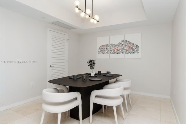 tiled dining area featuring a raised ceiling and an inviting chandelier