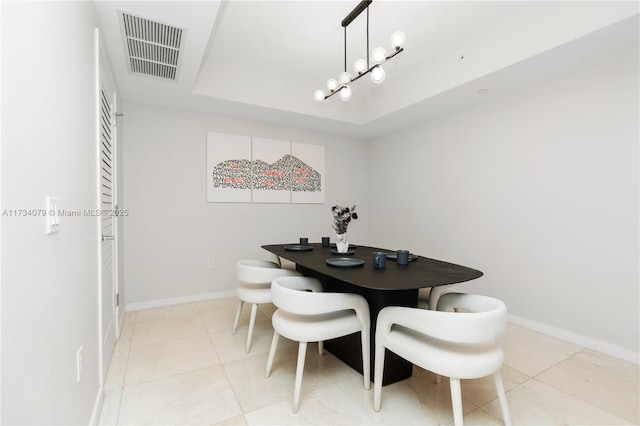 tiled dining space featuring a raised ceiling