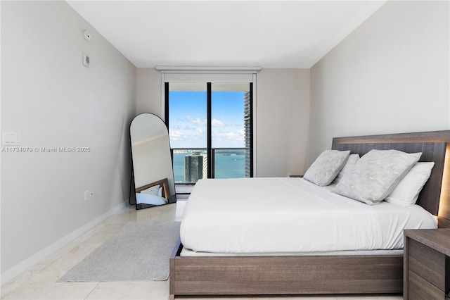 bedroom with access to outside, a wall of windows, and a water view