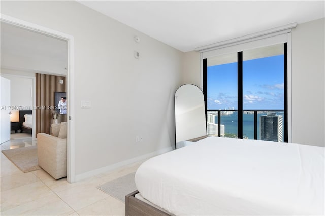 bedroom with a water view, expansive windows, and light tile patterned floors