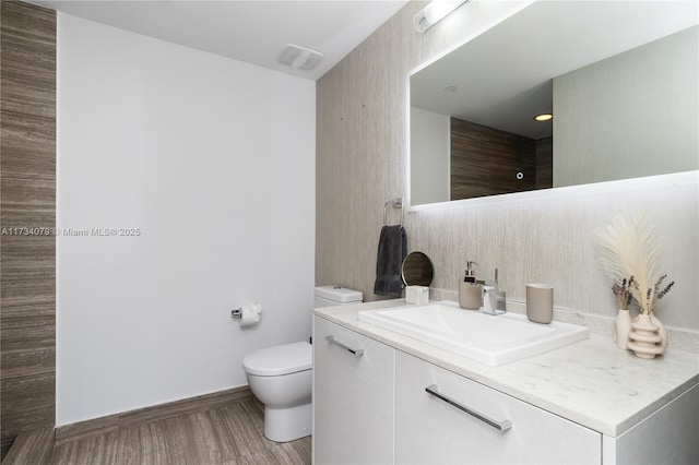 bathroom featuring vanity, wood-type flooring, and toilet