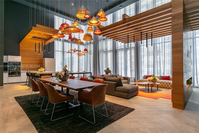 dining room featuring a high end fireplace, a chandelier, floor to ceiling windows, and a high ceiling