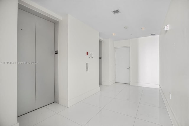 hall with elevator and light tile patterned floors