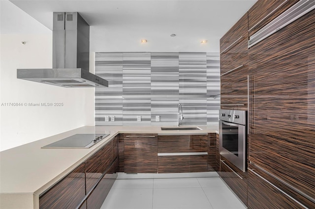 kitchen featuring sink, light tile patterned floors, black electric stovetop, island range hood, and oven