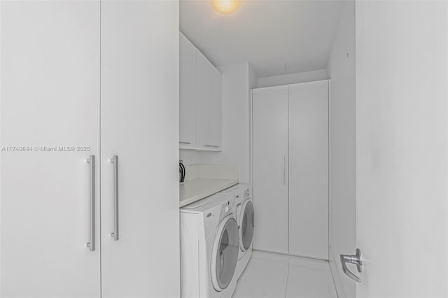 clothes washing area featuring cabinets, light tile patterned floors, and washer and dryer