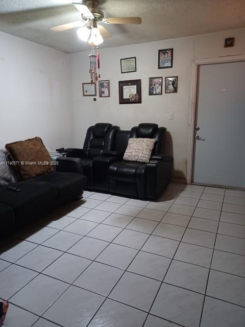 tiled living room with ceiling fan and a textured ceiling