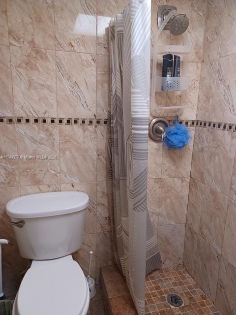 bathroom with tile walls, toilet, and walk in shower