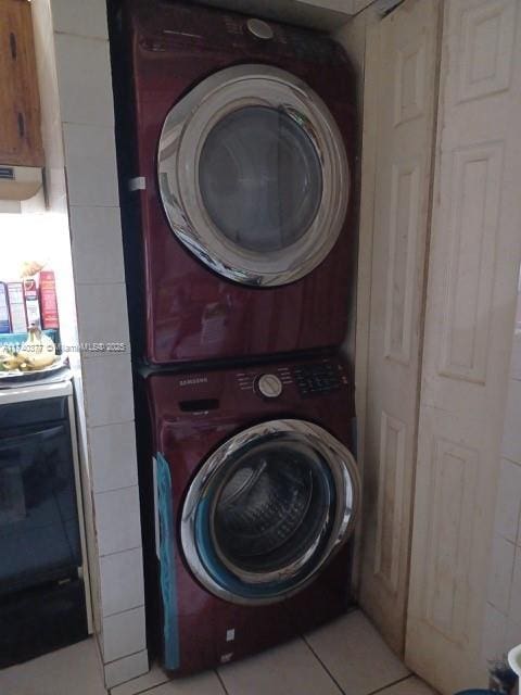 laundry area featuring stacked washing maching and dryer and light tile patterned flooring