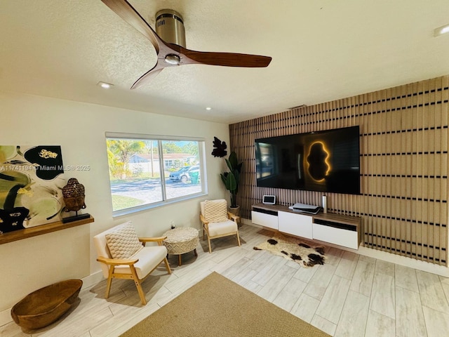 living area with a textured ceiling and ceiling fan