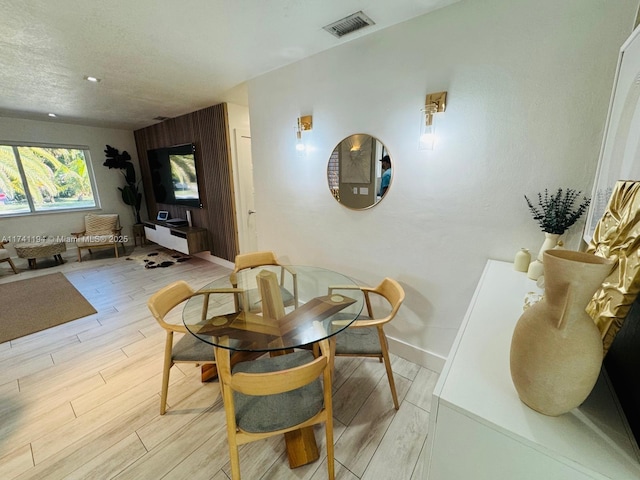 dining space with light hardwood / wood-style flooring and a textured ceiling