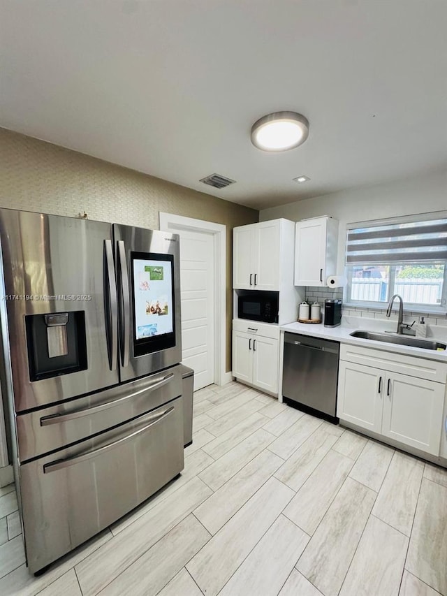 kitchen featuring stainless steel appliances, white cabinetry, sink, and decorative backsplash