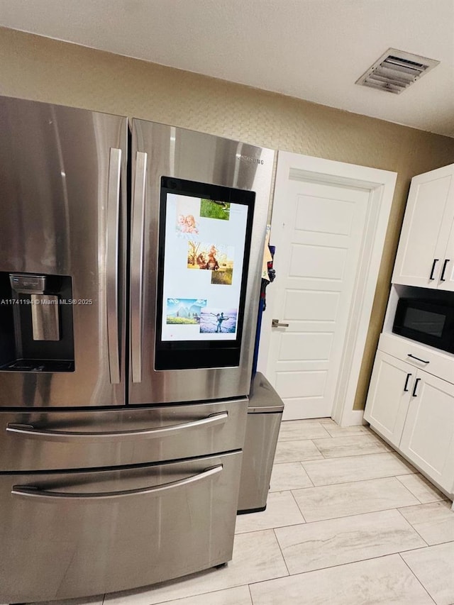 interior details with white cabinets and stainless steel refrigerator with ice dispenser