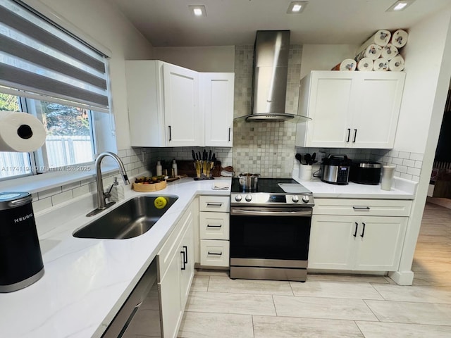 kitchen featuring wall chimney range hood, stainless steel electric range, and white cabinets