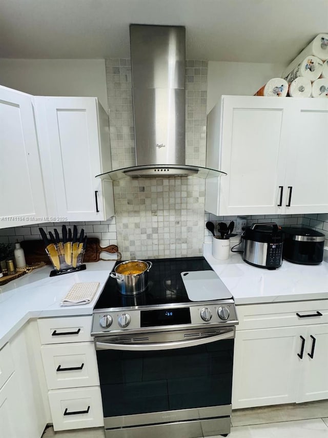 kitchen featuring white cabinetry, stainless steel electric range oven, backsplash, and wall chimney range hood