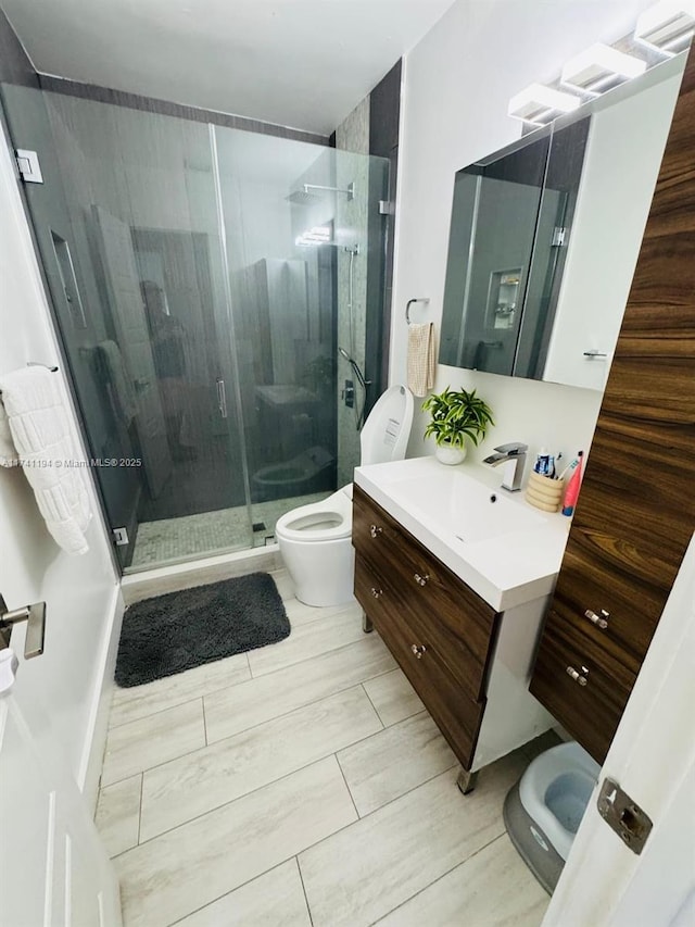 bathroom featuring vanity, toilet, and a shower with door