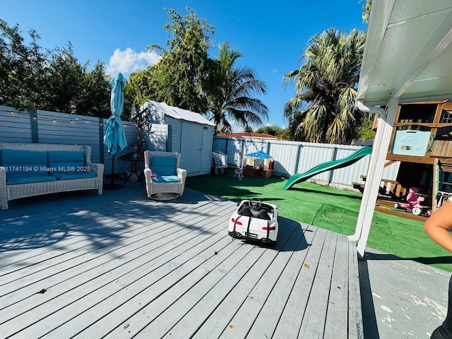 deck featuring a playground, outdoor lounge area, a yard, and a shed