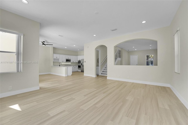 unfurnished living room with ceiling fan, sink, and light hardwood / wood-style floors