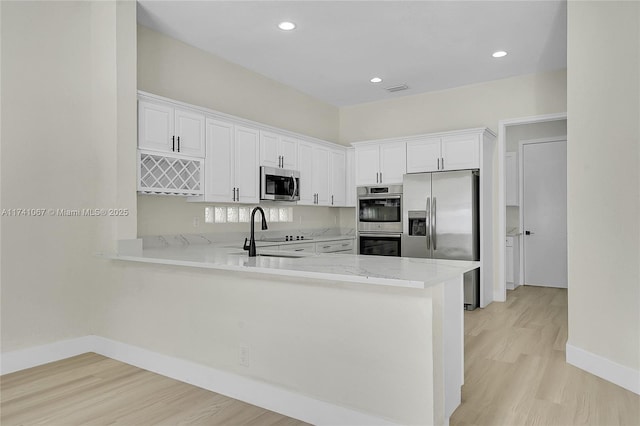 kitchen featuring appliances with stainless steel finishes, sink, white cabinets, and kitchen peninsula