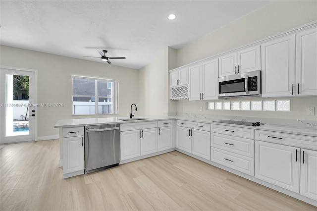 kitchen with sink, white cabinetry, light wood-type flooring, appliances with stainless steel finishes, and a wealth of natural light