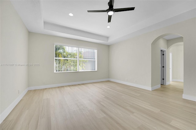 unfurnished room featuring ceiling fan, a raised ceiling, and light wood-type flooring