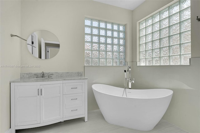 bathroom featuring vanity, plenty of natural light, and a tub to relax in