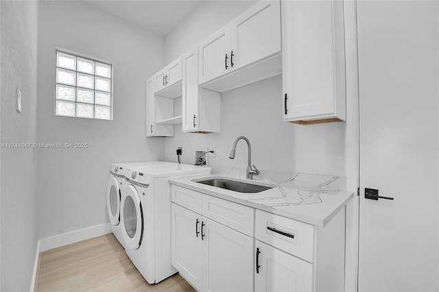 washroom featuring cabinets, washer and dryer, sink, and light hardwood / wood-style floors