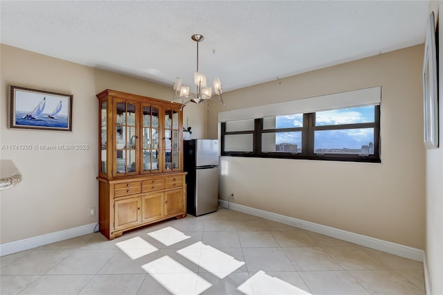 unfurnished dining area with light tile patterned floors, a textured ceiling, and an inviting chandelier