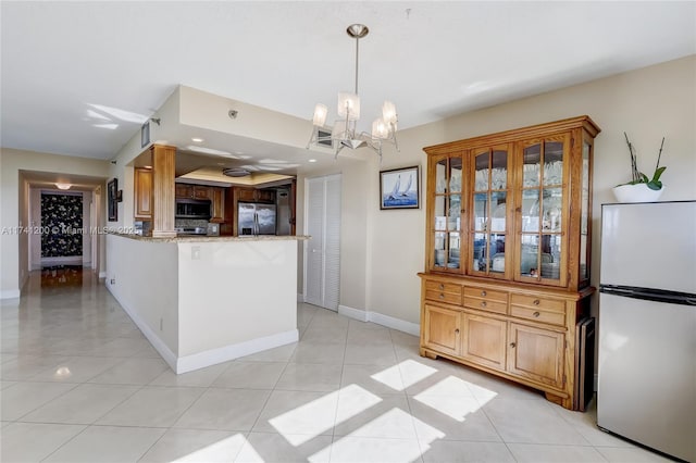 kitchen with light stone counters, refrigerator, light tile patterned floors, stainless steel fridge, and kitchen peninsula