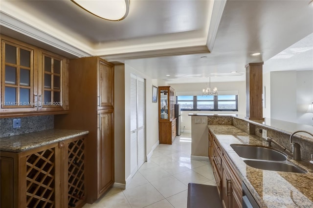 kitchen featuring pendant lighting, sink, decorative columns, and stone counters