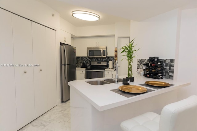 kitchen featuring white cabinetry, appliances with stainless steel finishes, kitchen peninsula, and decorative backsplash