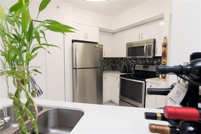 kitchen featuring decorative backsplash, white cabinets, and appliances with stainless steel finishes