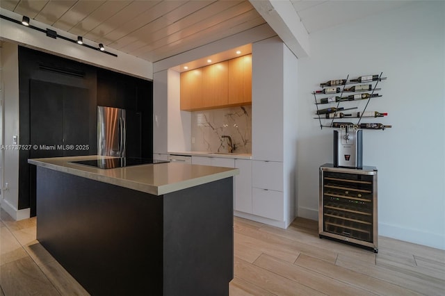 kitchen featuring stainless steel fridge, a center island, light hardwood / wood-style floors, black electric cooktop, and beverage cooler